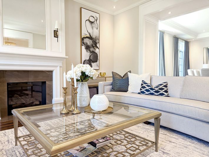 Living room with a fireplace, sofa, and coffee table, with neutral tones and elegant decor.