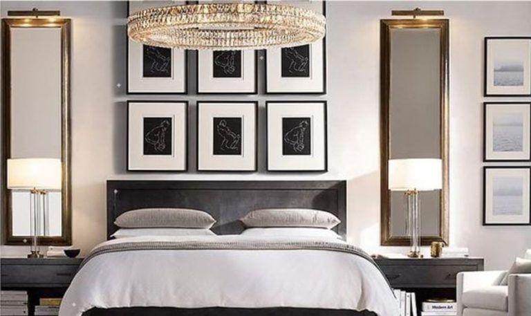 Bedroom with bed, nightstands, mirrors, artwork, and chandelier.