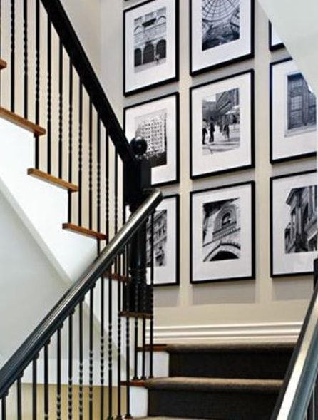 Staircase with black railing and framed black and white photos on the wall.