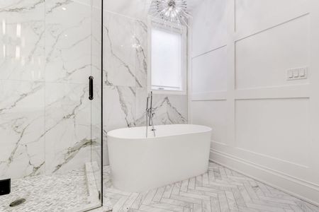 Luxurious white marble bathroom with freestanding tub and glass shower.