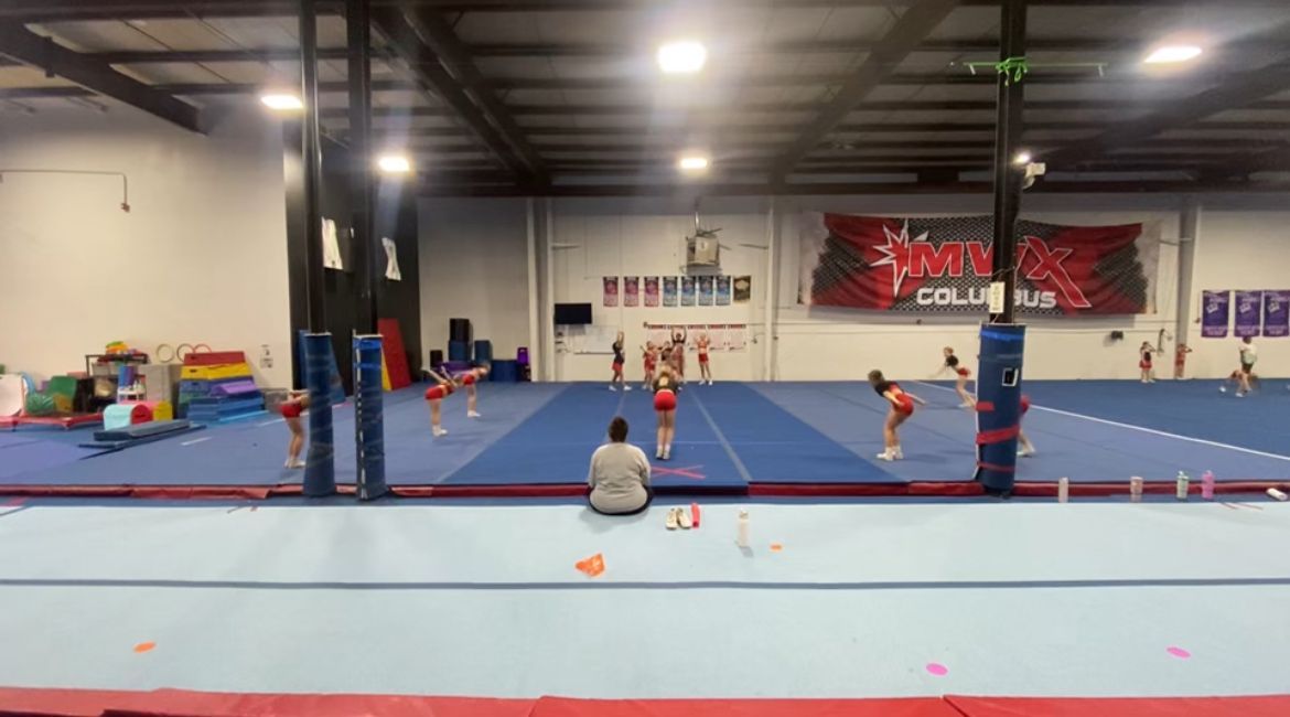 A group of people are practicing gymnastics in a gym.