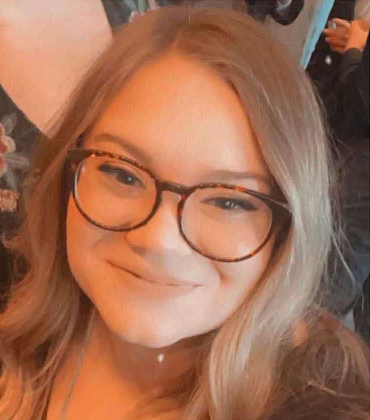 A close up of a woman wearing glasses and smiling.