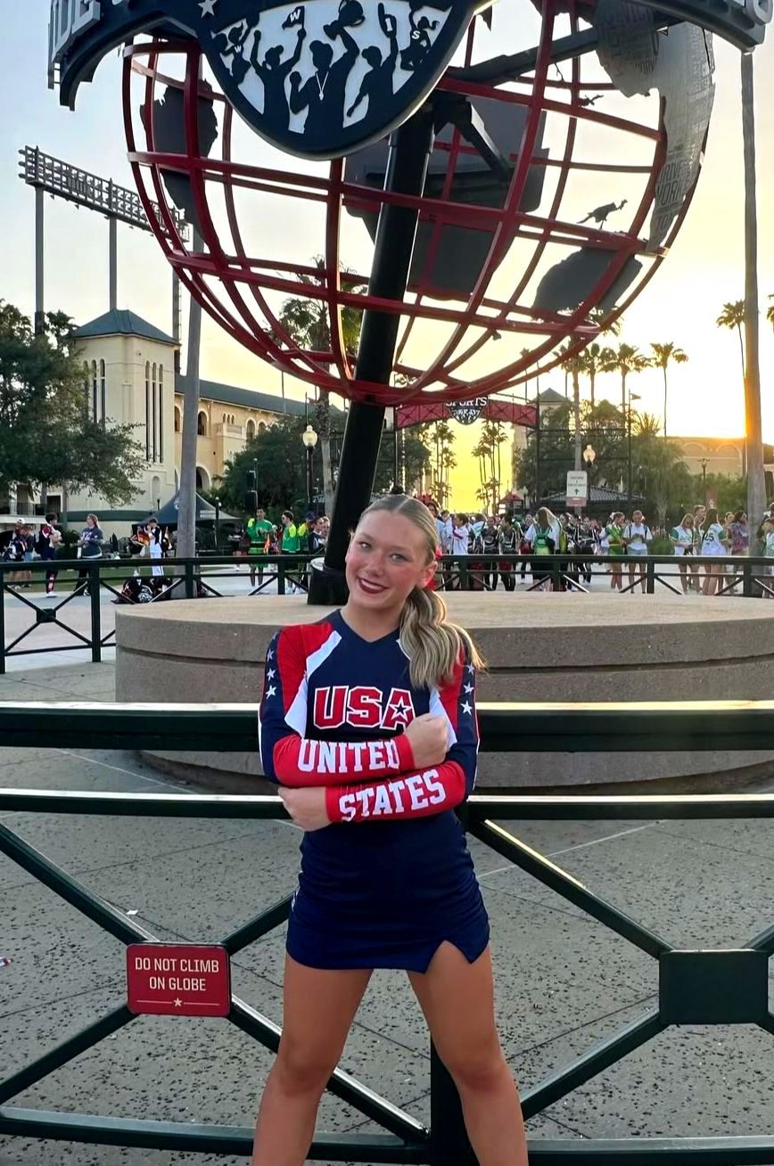 A cheerleader from the united states is standing in front of a statue.