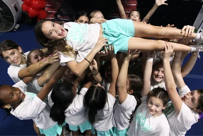 Five smiling girls pose together, a birthday hat and face paint present.