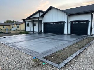 A house with two garage doors and a concrete driveway in front of it.