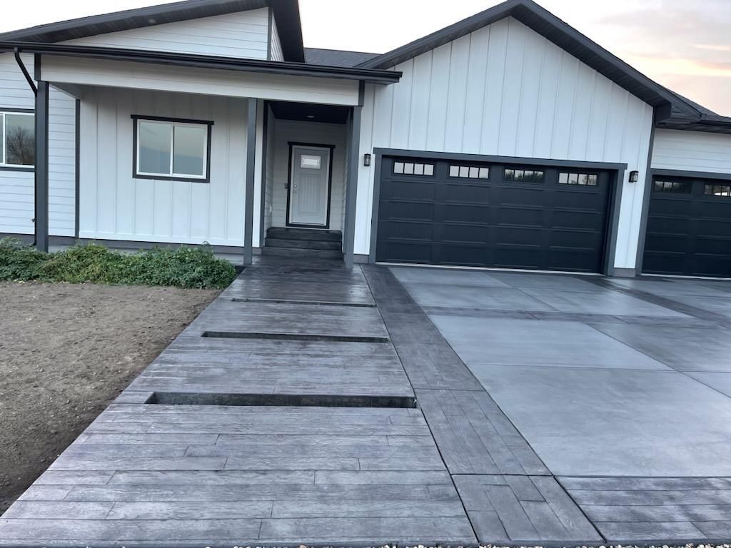 A white house with black garage doors and a concrete driveway