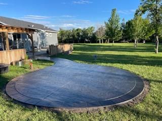 A large circular concrete patio in the middle of a lush green field.