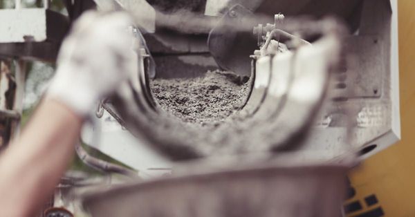 A person is pouring concrete into a bucket.