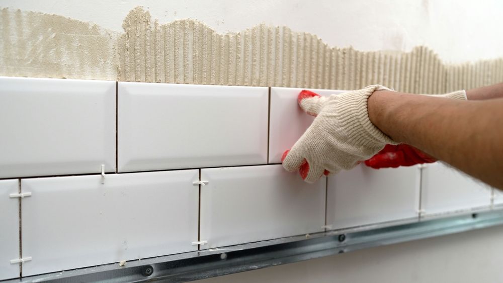 A person is installing tiles on a wall.