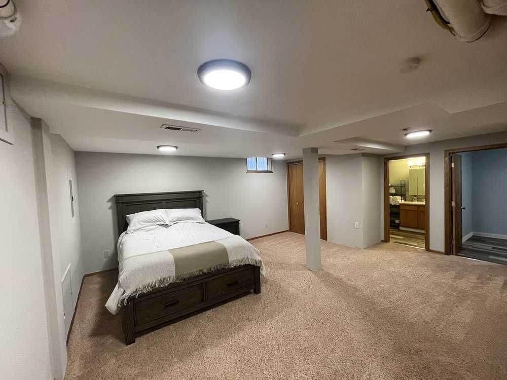 Bedroom with bed, carpet, and neutral-colored walls. Doorway leads to bathroom.