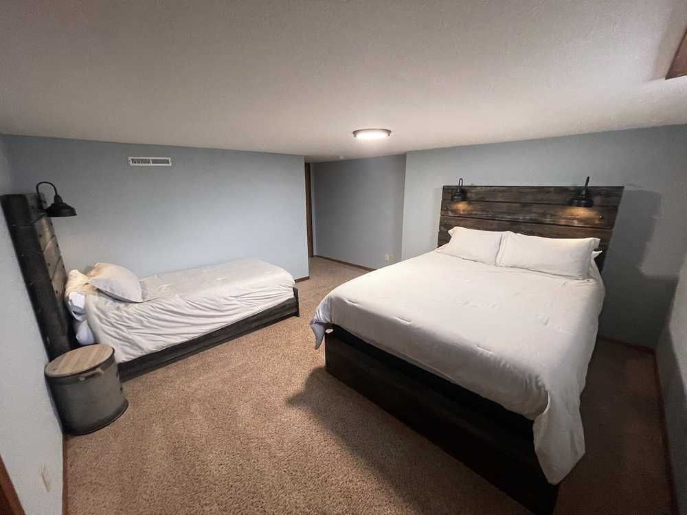 Bedroom with two beds, one double, one twin, blue walls, dark wood headboards, and sconce lighting.