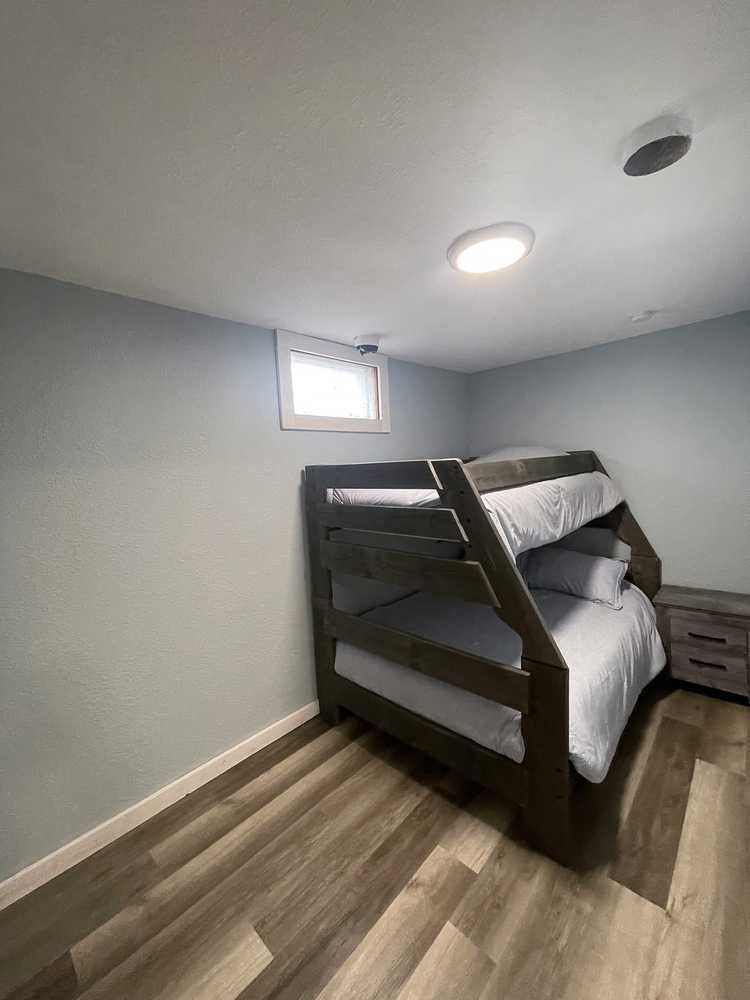 Bunk beds in a small room with grey walls and wood-look flooring.