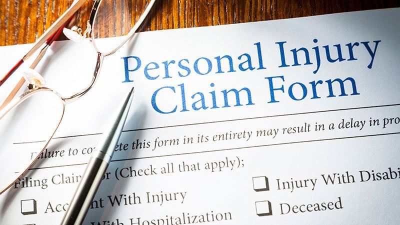 Glasses and Pen lying on Personal injury claim form