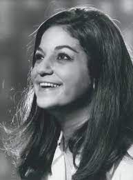 Een vrouw met lang haar lacht op een zwart-witfoto.