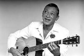 Een zwart-witfoto van een man die een akoestische gitaar speelt.