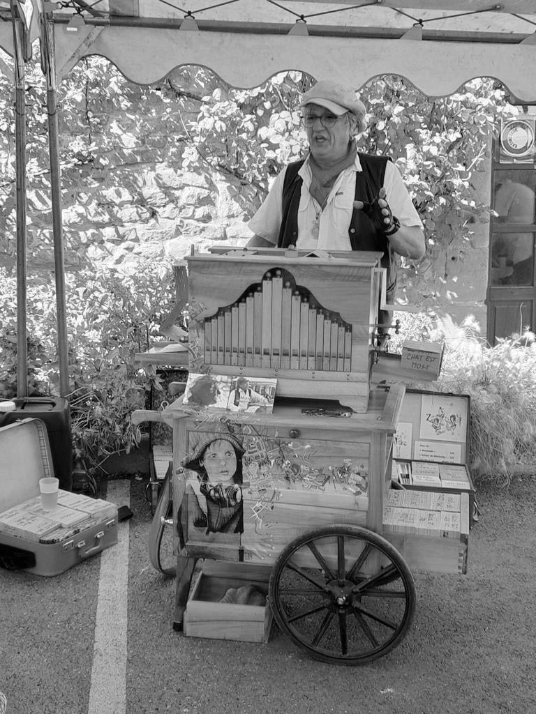 Een zwart-witfoto van een man die een orgel op een kar bespeelt.