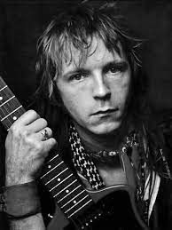 Een zwart-witfoto van een man die een gitaar vasthoudt.