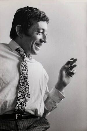 Een zwart-witfoto van een man die een stropdas draagt en lacht.