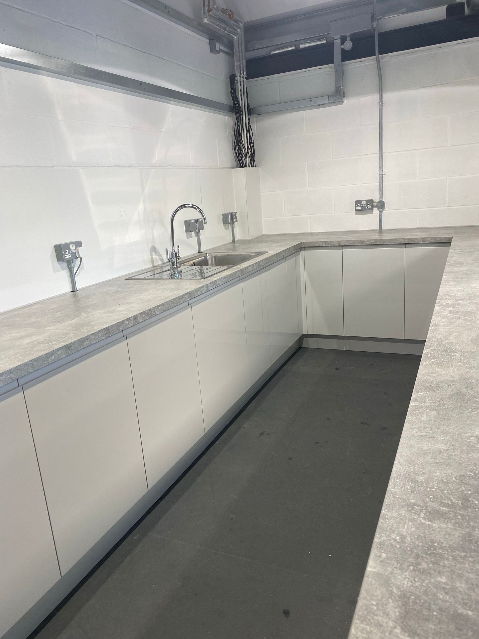 An empty kitchen with white cabinets and a sink