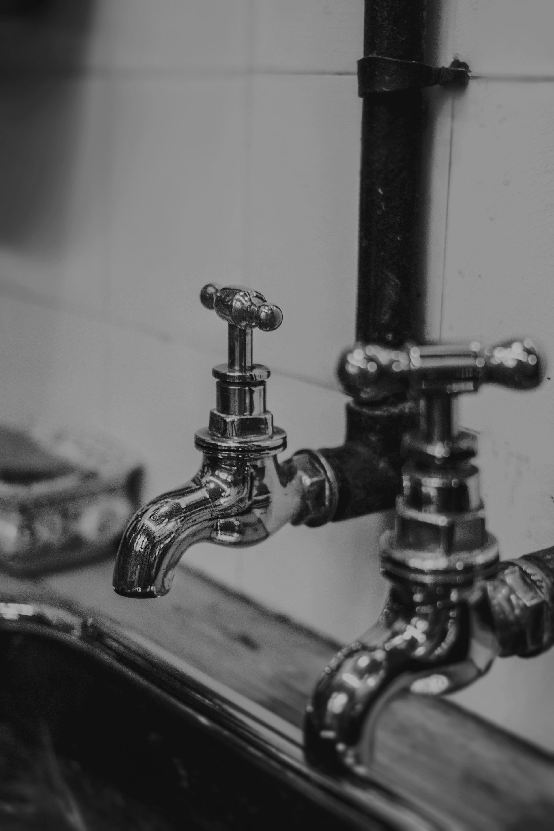 A black and white photo of two faucets on a sink.