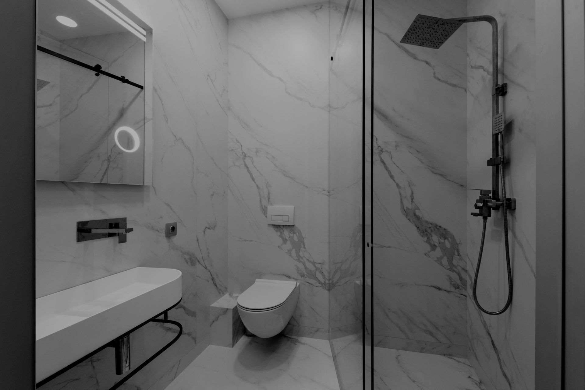 A black and white photo of a bathroom with a toilet , sink and shower.
