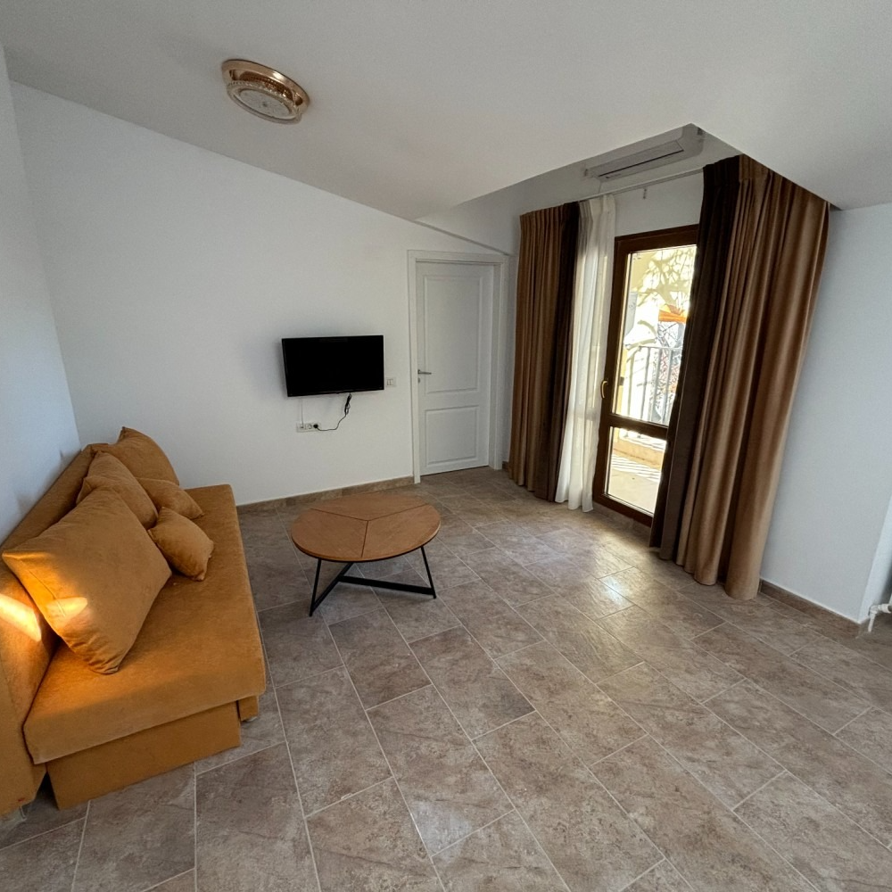 A living room with a couch and a television on the wall