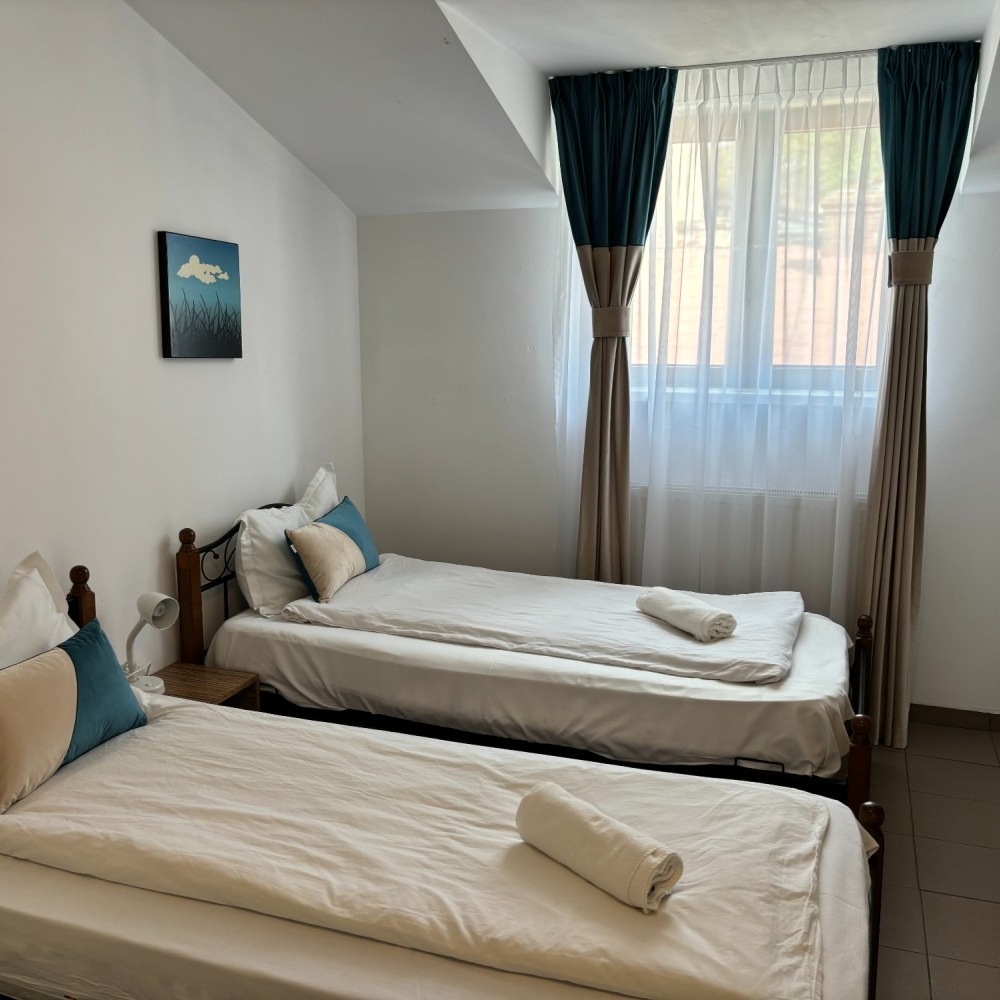 A bedroom with two beds and a window with curtains