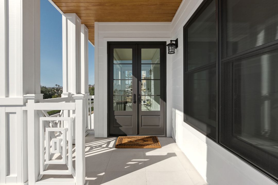 A porch with a black door and a white railing.