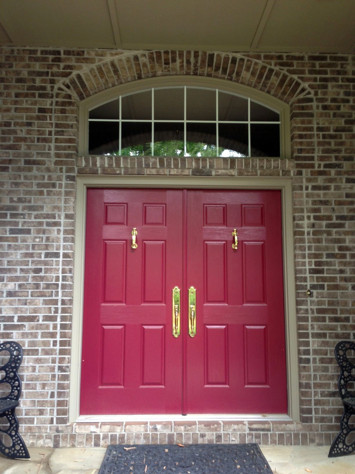 A red double door with gold handles on a brick building