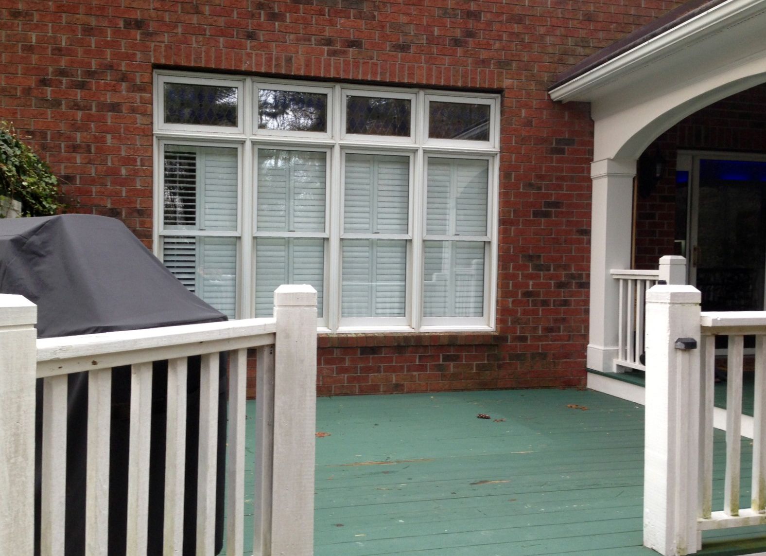 A brick house with a white fence and a large window