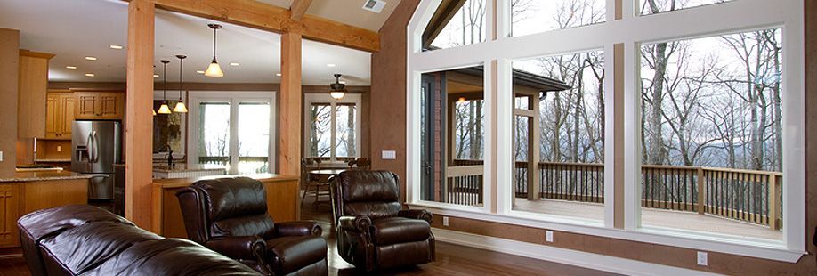 A living room with a lot of windows and a couch and chairs