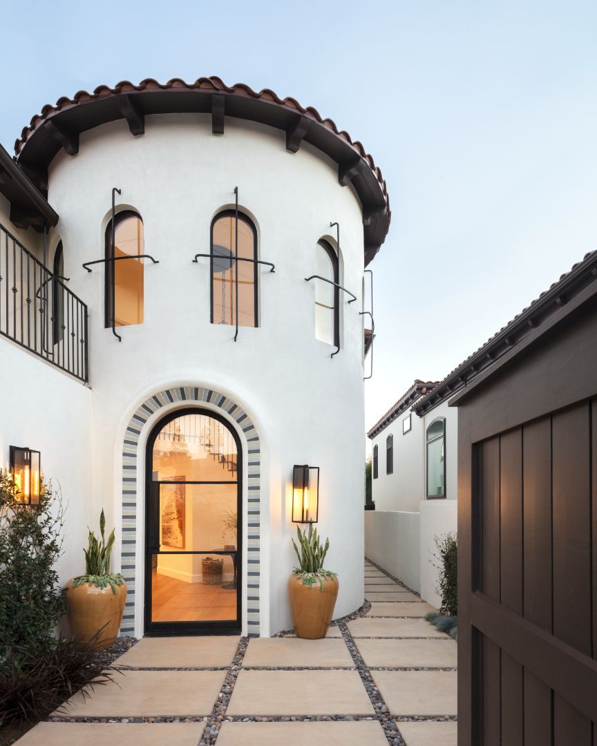 A white building with arched windows and potted plants in front of it