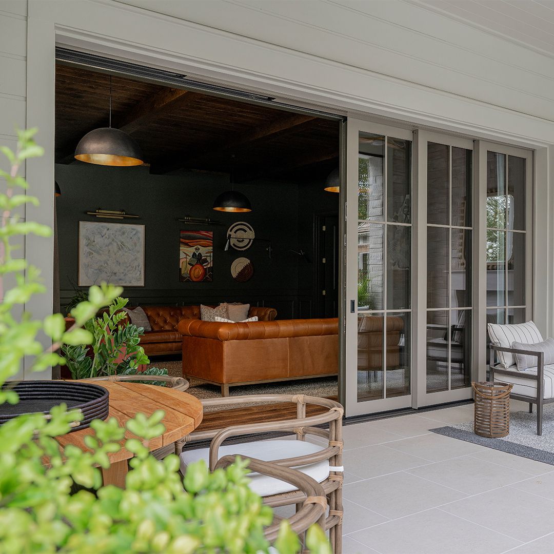 A living room with a couch , chairs , table and sliding glass doors.