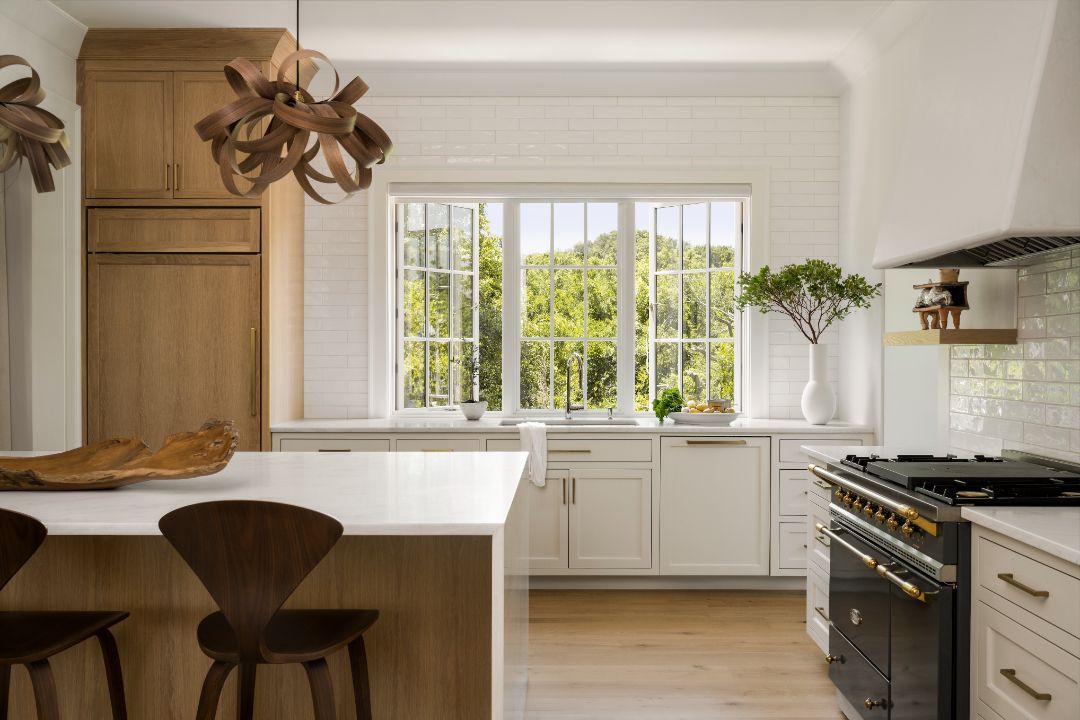 A kitchen with white cabinets , a black stove and a large window.
