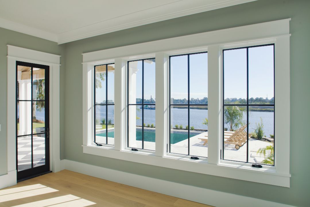 A room with a lot of windows and a view of a lake.