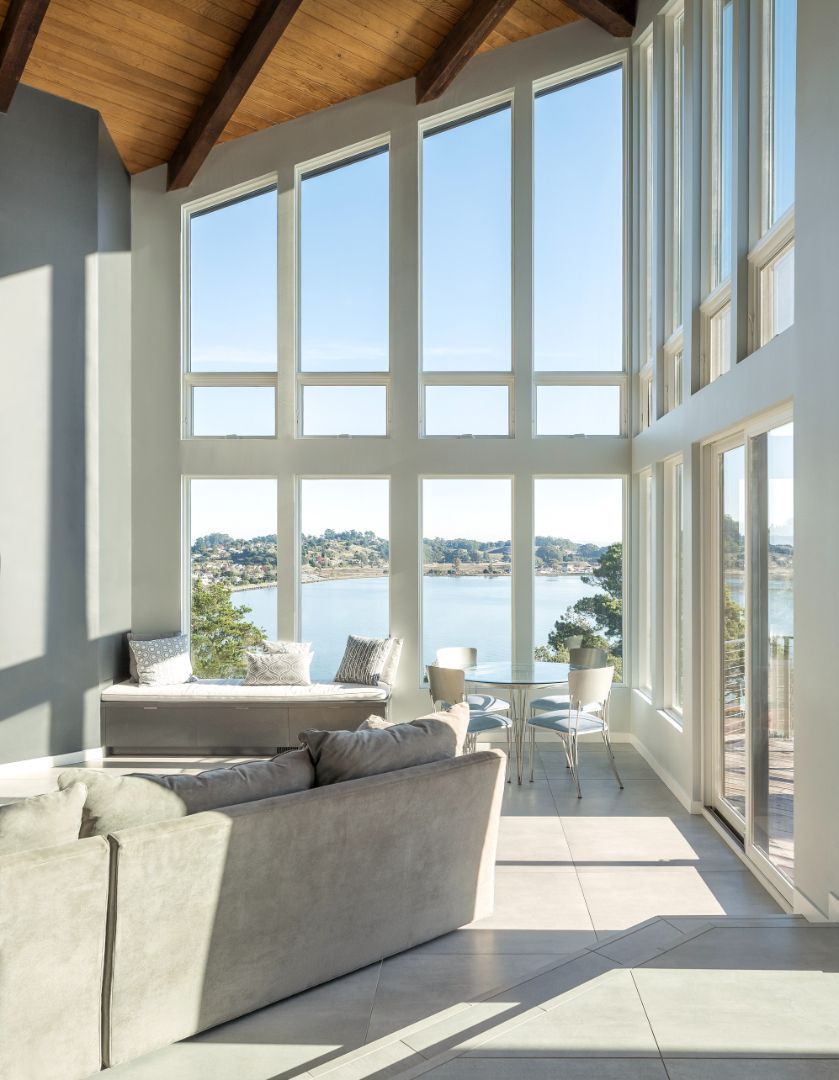 A living room with a couch and lots of windows overlooking a body of water
