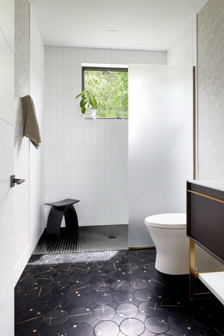 A bathroom with a toilet , shower and window.