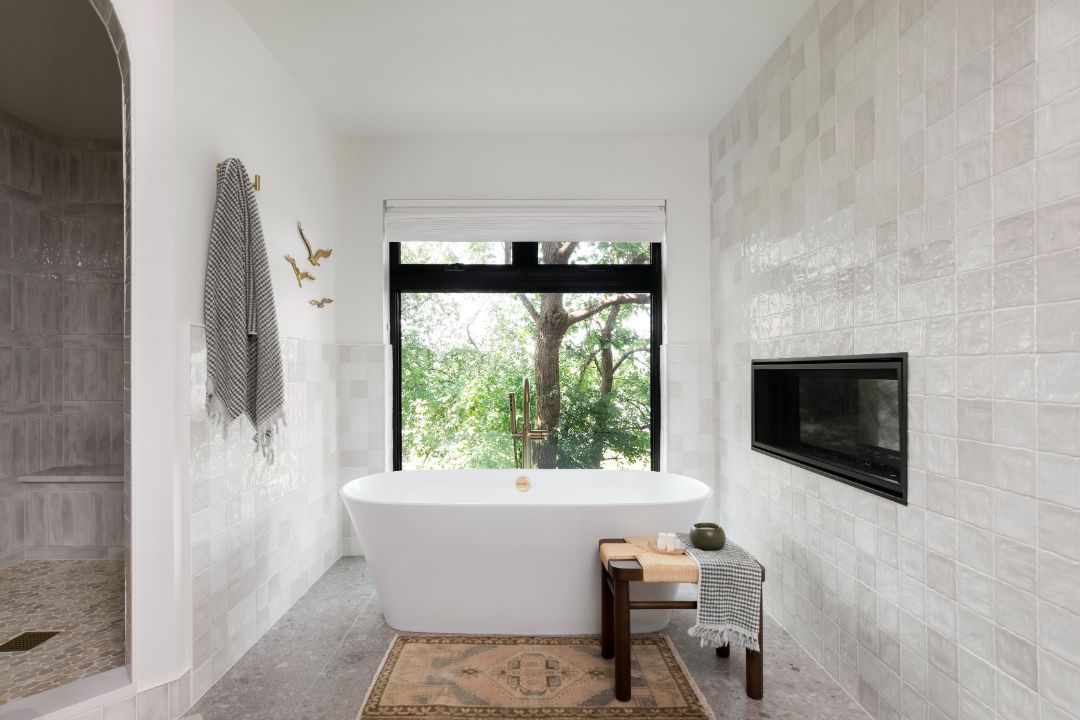 A bathroom with a tub and a window with a view of a tree.