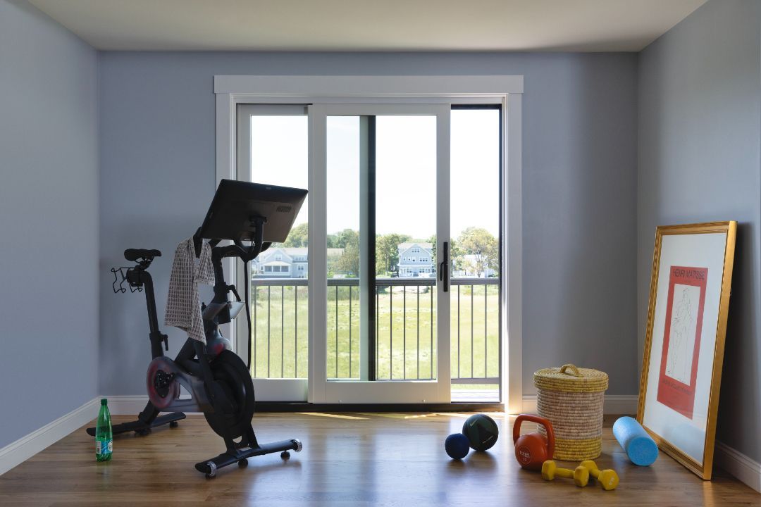 A room with a bike , dumbbells , and a picture on the wall.