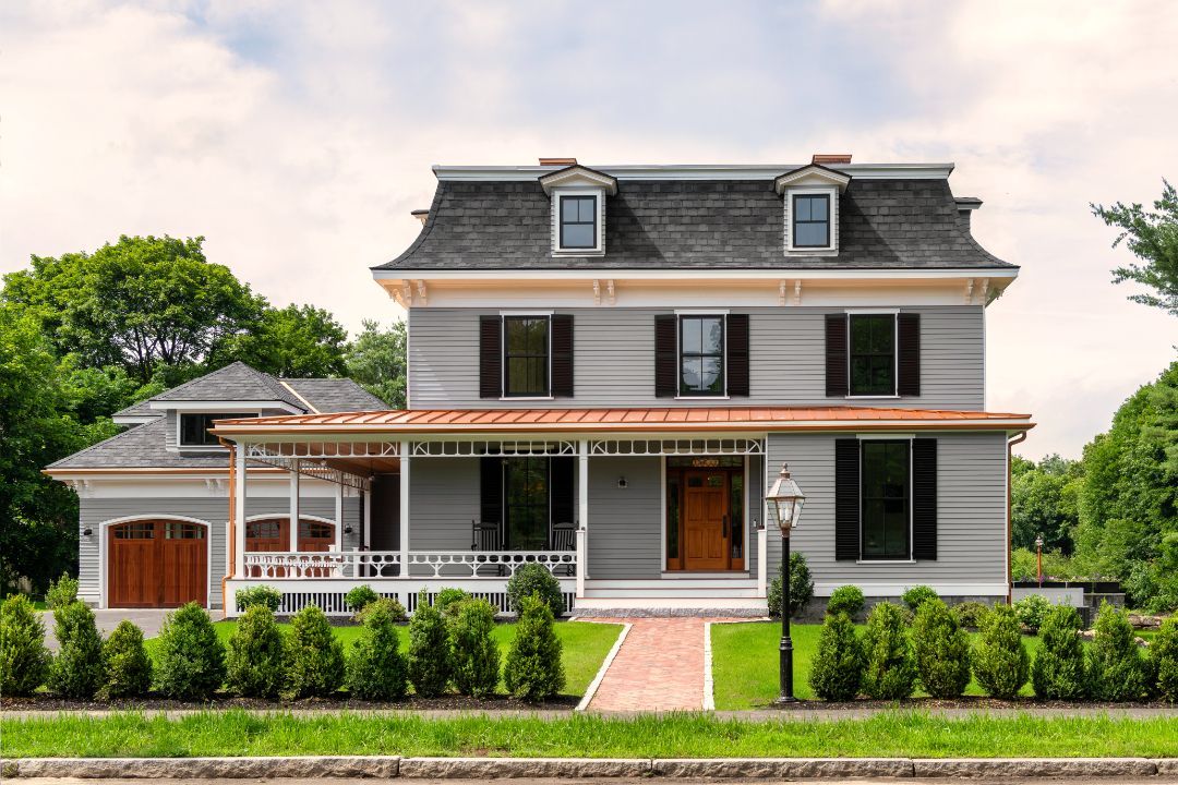 A large house with a large porch and a brick walkway leading to it.