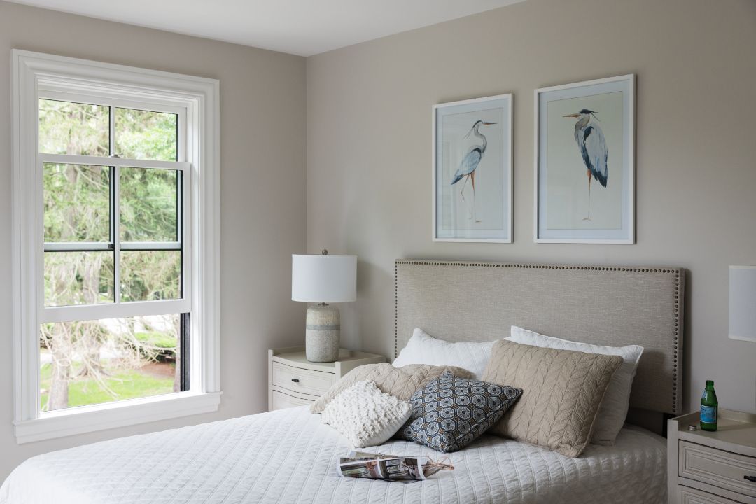 A bedroom with a bed , nightstand , lamp and two pictures on the wall.