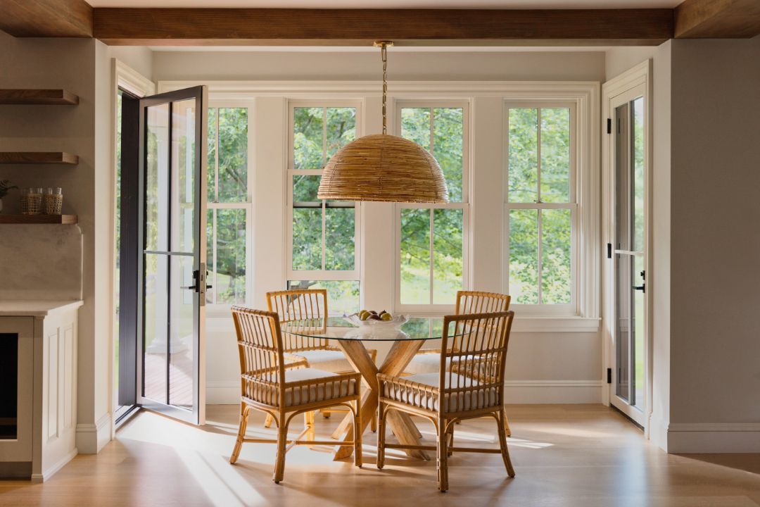 A dining room with a table and chairs and a large window.
