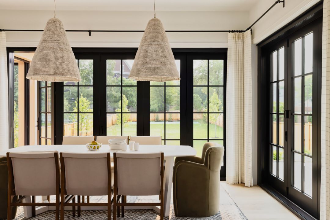 A dining room with a table and chairs and a lot of windows.