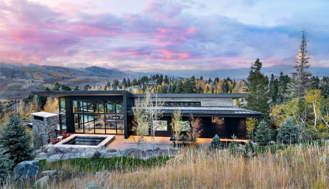 A large house is sitting on top of a hill in the middle of a forest.