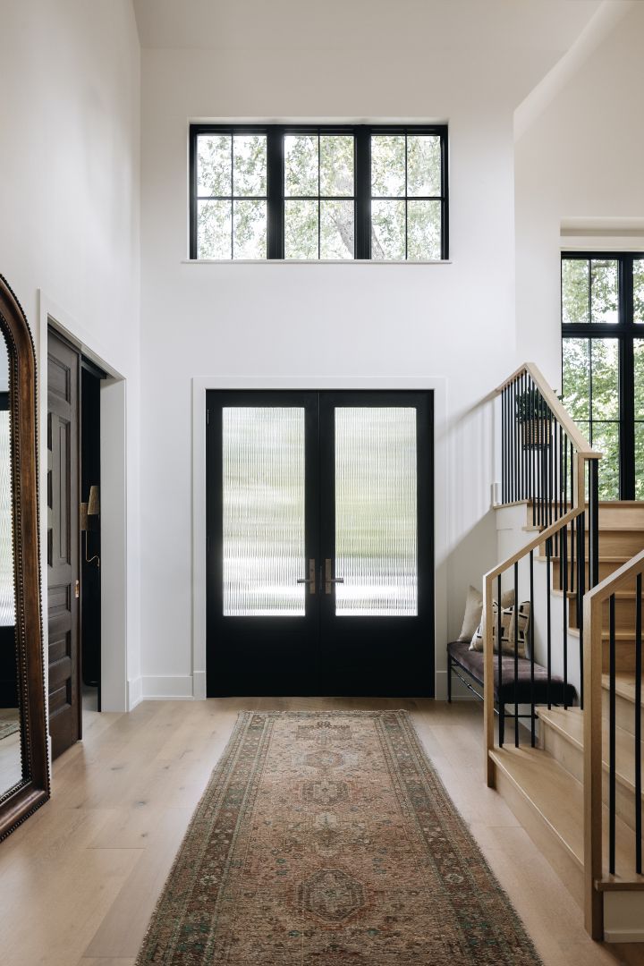 A hallway in a house with black doors and stairs.