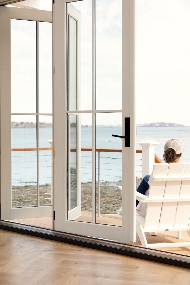 A man is sitting in a chair on a balcony overlooking the ocean.
