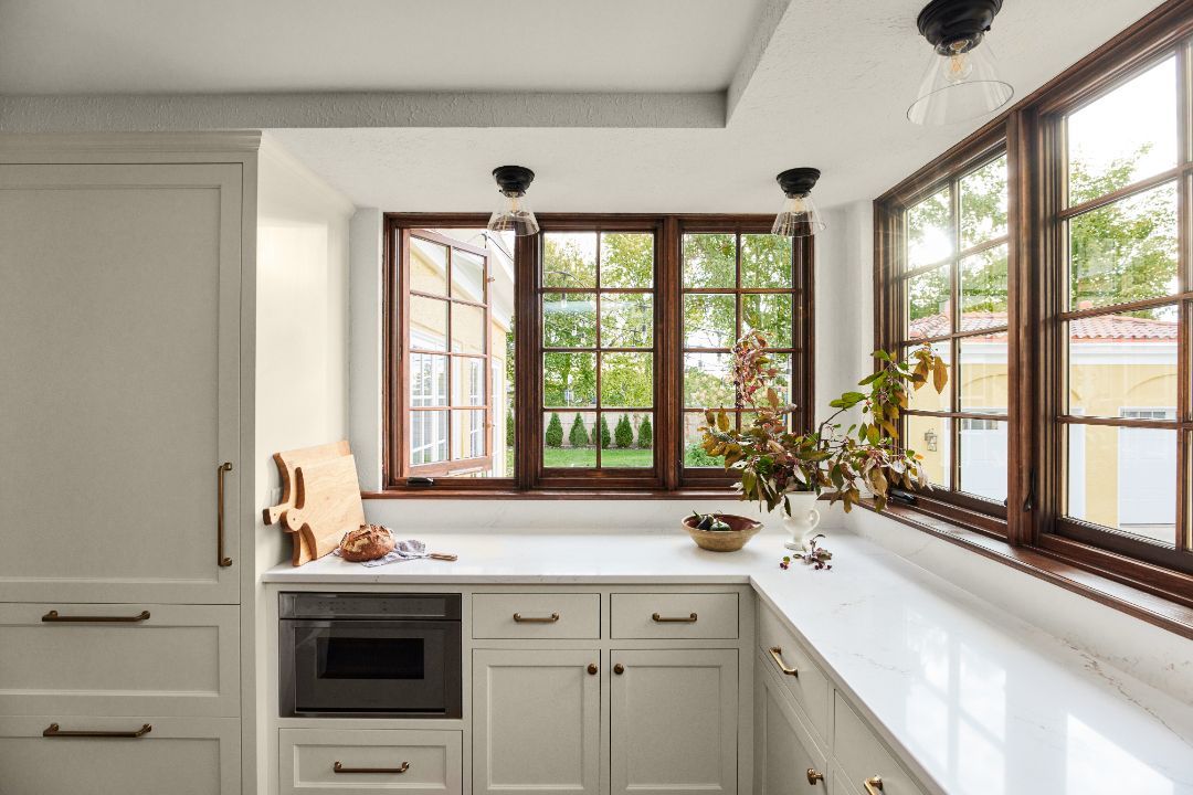 A kitchen with a lot of windows and white cabinets.