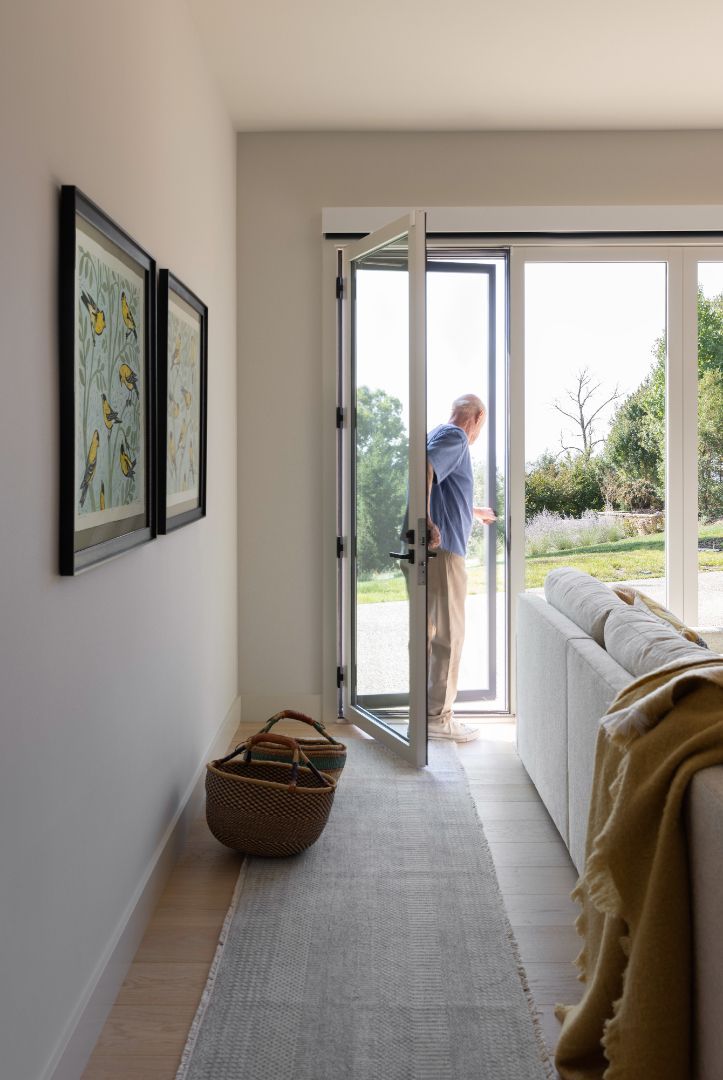 A man is opening a sliding glass door in a living room.