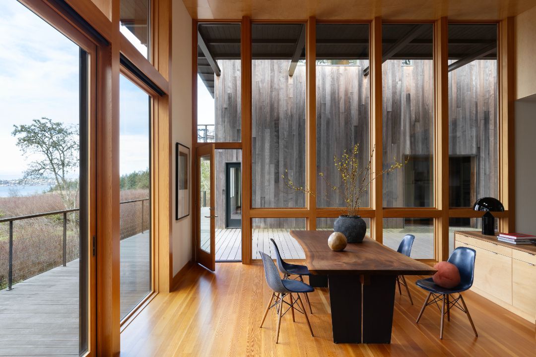 A dining room with a table and chairs and lots of windows