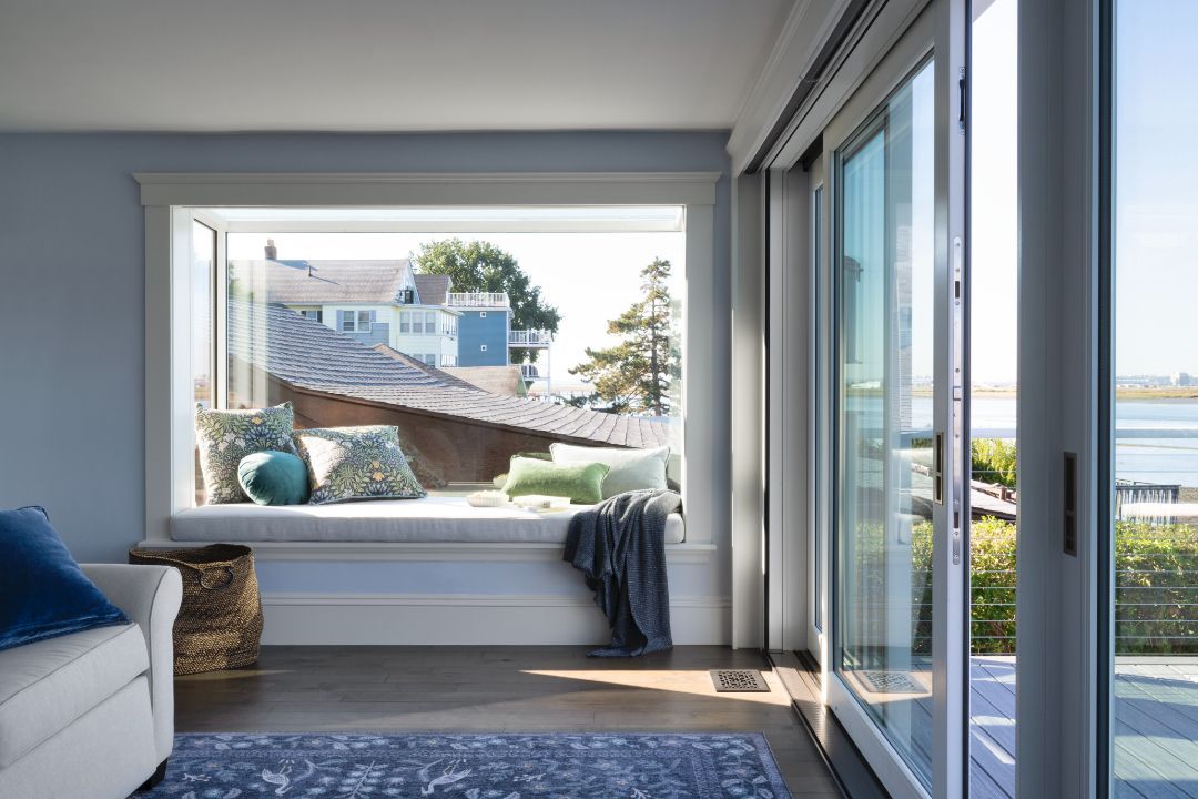A living room with a large window seat and sliding glass doors.